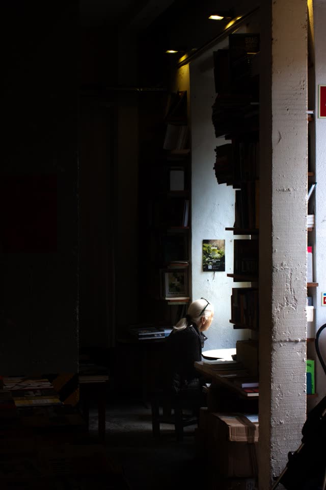 A woman reading by the window light in a bookshop