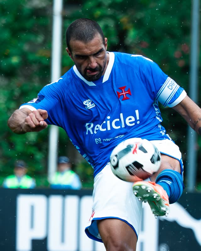 A captain in blue strikes a volley, the ball sharp in the foreground